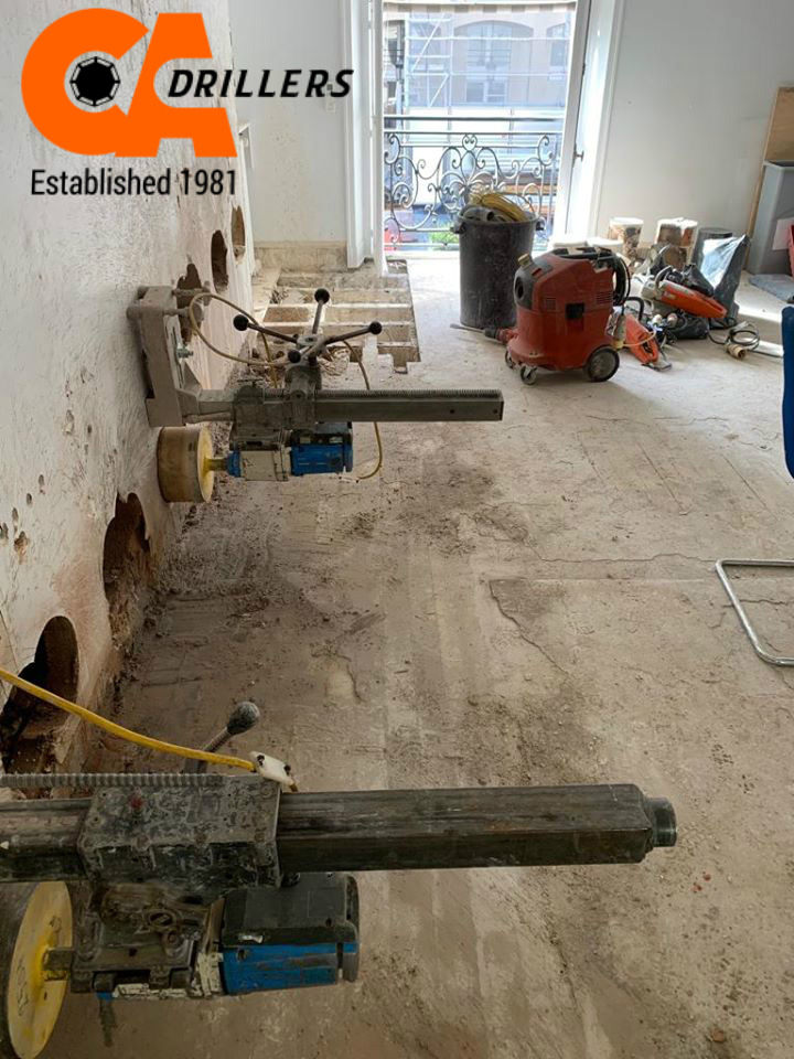 Heavy-duty rig-mounted diamond core drills setup for concrete stitch drilling on an indoor construction site by CA Drillers.